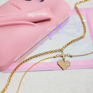 Close-up of gold double-layer necklace with crystal heart and cross pendants