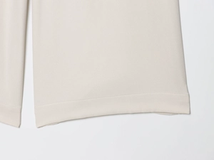 Detailed view of beige twill fabric hem with precise double-needle stitching and texture