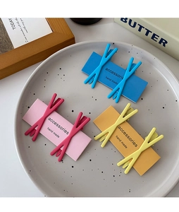 Detail of candy-colored cross hair clips in blue, pink, and yellow with matte finish