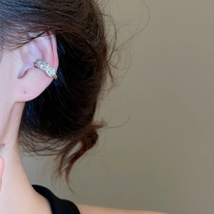 Macro shot of silver ear cuff set with pavé cubic zirconia on person's upper cartilage