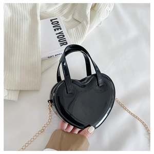 Detail of heart-shaped black patent leather mini bag with gold chain and zipper closure
