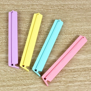 Set of colorful plastic food sealing clips in purple, yellow, and blue on wood surface