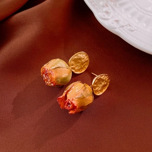 Detailed view of vintage gold earrings with realistic rose buds and hammered texture