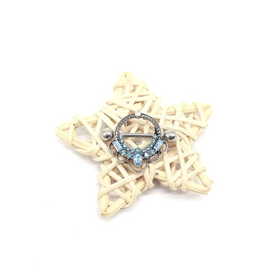 Close-up of sky blue teardrop crystal nipple ring with intricate hollow shield design