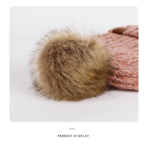 Detail of a fluffy brown pom-pom and pink mixed knit texture on a winter beanie cap