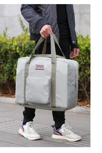 Close-up of a large grey nylon travel bag with olive green handles in a lifestyle setting