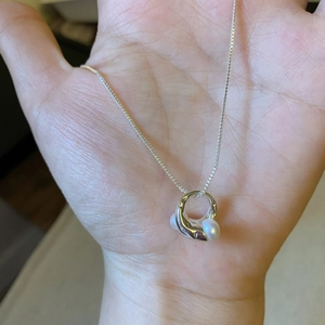 Dettaglio di un ciondolo asimmetrico in argento placcato oro 18K con perle su catena box