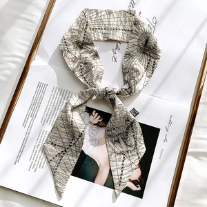 Detail of beige silk scarf with vintage map print tied in a bow on a magazine background