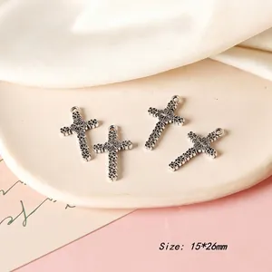 Macro detail of a 15x26mm vintage alloy cross charm with intricate hollow patterns for DIY