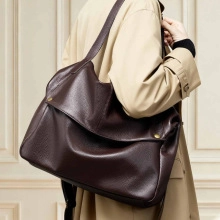 Detail of dark brown lychee leather bucket bag with metallic buckle and shoulder strap