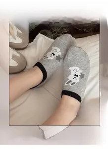 Detail of grey low-cut cotton sock with cartoon rabbit pattern and non-slip silicone heel