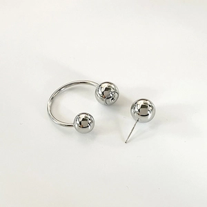 Macro view of polished silver metal horseshoe ring and stud earring with mirror finish