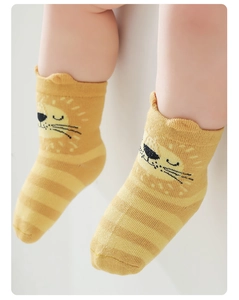 Close-up of yellow striped baby socks with 3D lion design and wave-edge cuffs
