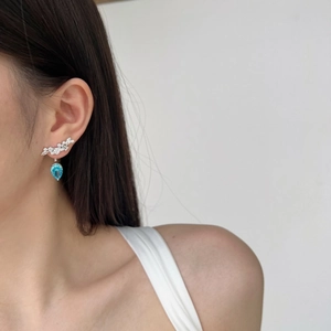 Detail of silver drop earring with blue heart zircon and leaf-shaped pavé crystals
