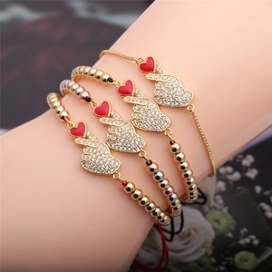 Detail of four-piece gold bracelet set with red enamel heart gesture and pavé crystals
