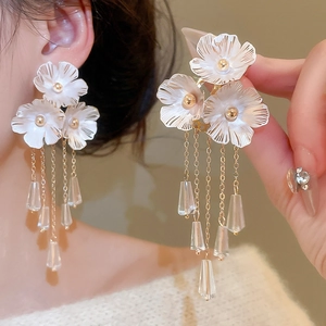 Detailansicht der eleganten gold-weißen Blumen-Ohrringe mit langen Quasten und Anhängern