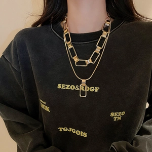 Close-up of double-layer gold chain necklace with chunky links and rectangular pendant
