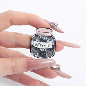 Cute cat happy pills enamel pin held by hand featuring funny grey kittens cartoon badge
