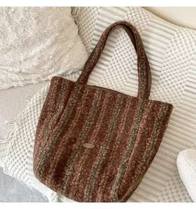Detailed view of striped wool tote bag with handmade metal tag on plush textured fabric