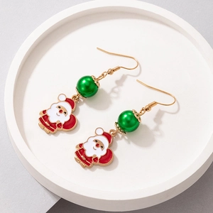 Detailed close-up of Santa Claus festive earrings with colorful pearls on a white tray