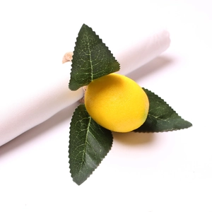 Macro shot of a lifelike artificial lemon and green leaves on a white napkin ring