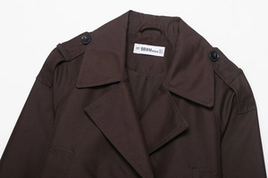 Detailansicht des dunkelbraunen Trenchcoat-Kragens mit Schulterklappe und dem S-Größenetikett