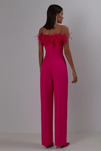 Detail of rose red jumpsuit featuring ostrich feather trim and elegant high-waist cut