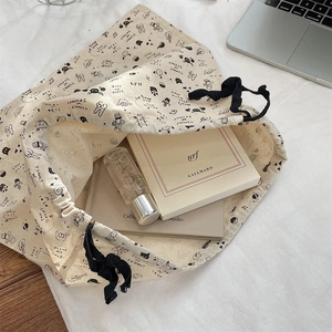 Detail of cartoon printed cotton drawstring bag showing capacity with books and spray bottle