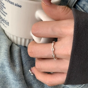 Close-up of minimalist s925 silver pig nose anchor chain ring on finger with denim outfit