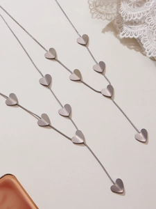 Detail view of silver Y-shaped necklace with brushed heart pendants on snake chain