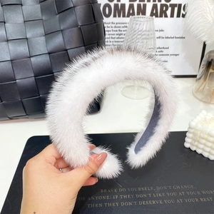 Close-up of fluffy white plush headband held by hand with high-quality faux mink fur texture