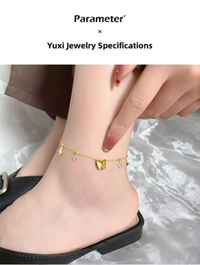 Macro detail of a gold butterfly anklet with matte charms and sparkling rhinestones