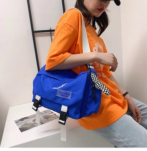 Close-up of blue nylon messenger bag with white strap and black buckle closure
