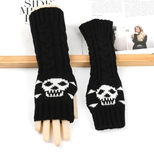 Detail of black knitted arm warmer featuring white skull jacquard and fingerless design