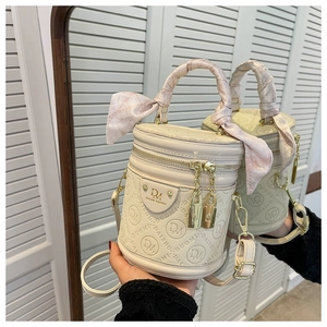 Detail view of off-white cylinder bag with logo embossing and pink silk scarf wrap