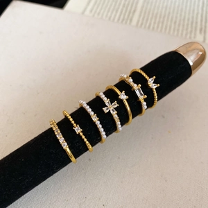 Detailed close-up of 6 gold rings set with pearls and zircon on a velvet stand