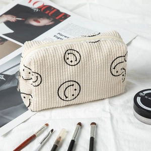 Detail of corduroy toiletry bag with smiley embroidery and makeup accessories