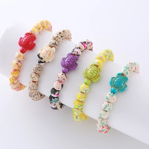 Close-up of colorful turtle charms and spotted beads on various stone bracelets