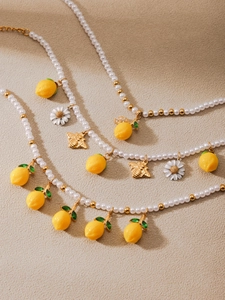 Detailed view of beaded pearl necklaces featuring lemon, bee, and daisy charms