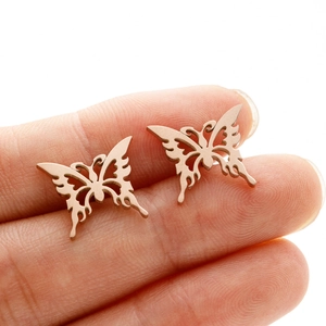 Macro view of rose gold hollow butterfly stud earrings held between fingertips