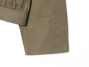 Detail of olive green twill coat cuff featuring precise double stitching and fabric texture