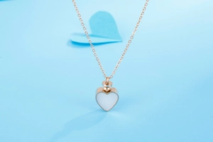 Détail du collier cœur en or rose avec insert en nacre sur fond bleu clair