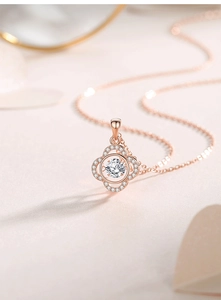 Macro detail of rose gold four-leaf clover pendant with dancing stone and pavé accents