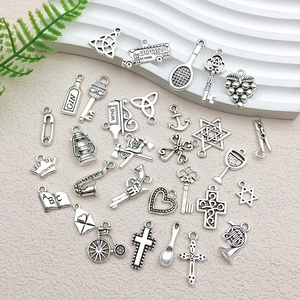 Flat lay of vintage silver alloy charms featuring keys, crowns, and crosses for DIY jewelry