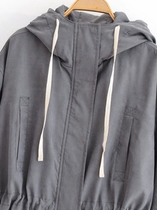 Detail of dark grey hooded windbreaker featuring contrasting cream-colored drawstrings