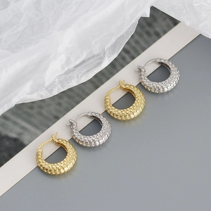 Detail of s925 silver hoop earrings with textured grainy surface in gold and silver finish
