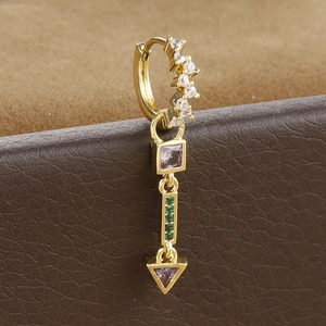 Macro shot of gold teardrop earrings with purple zircons and green diamond accents