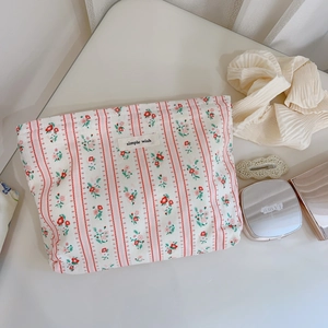 Détail de la trousse à maquillage en coton à fleurs rouges et étiquette tissée