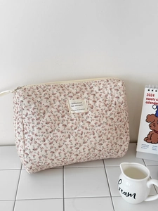 Close-up of quilted floral corduroy makeup bag with white fabric label and metal zipper