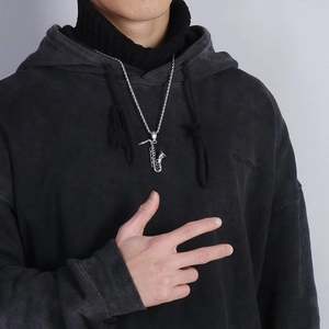 Polished stainless steel saxophone pendant necklace worn over a black hoodie